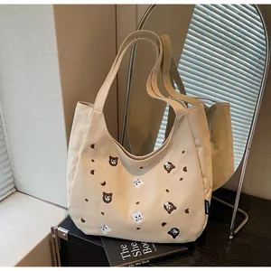 Close-up of animal embroidery and soft canvas texture on the beige tote shoulder bag