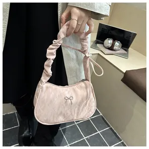 Sac à bandoulière rose plissé avec nœud argenté et anse froncée en mise en situation réelle