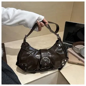 Close-up of brown glossy handbag with pleated leather, metal buckle and silver studs