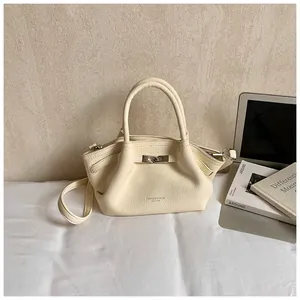 Detail of cream white lychee leather bucket bag with silver metal clasp and handles