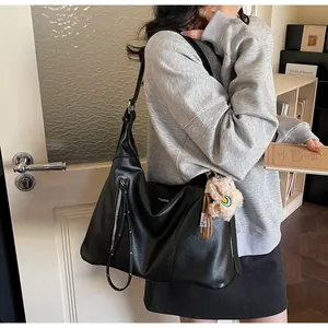 Détail du sac cabas en simili cuir noir avec fermeture éclair argentée et breloque en peluche
