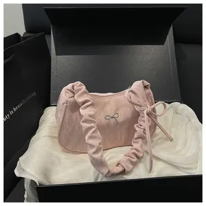 Détail d'un sac en satin rose avec anse plissée et nœud argenté en boîte cadeau
