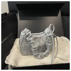 Gros plan du sac plissé argenté avec nœud papillon dans un coffret cadeau luxueux
