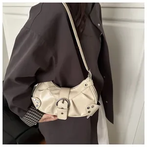 Detail of beige Y2K crescent bag featuring pleated faux leather and silver rivets