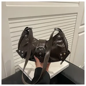 Close-up of a dark brown glossy leather crescent bag with silver buckles and stud details
