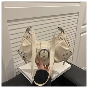 Detail of cream crescent bag featuring silver rivets and a large metal buckle detail