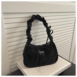 Détail du sac plissé noir avec pendentif nœud argenté et design de poignée froncée