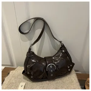 Detailed close-up of dark brown glossy leather shoulder bag with punk silver rivets