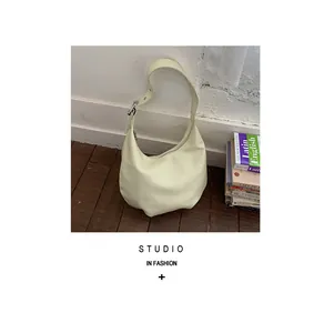 Close-up of crescent hobo bag in creamy yellow leather with adjustable strap and silver buckle