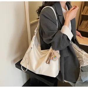 Détail du sac hobo blanc minimaliste avec fermeture éclair latérale et ours en peluche