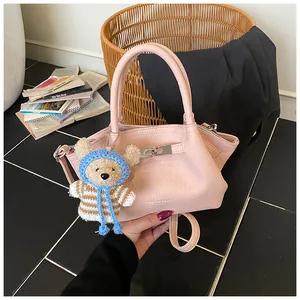 Detail of pink lychee leather bucket bag with metal buckle and cute bear pendant