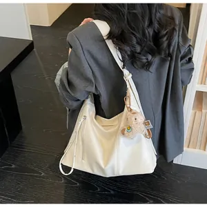 Vue arrière du mannequin portant un grand sac hobo blanc crème avec charm alpaga peluche