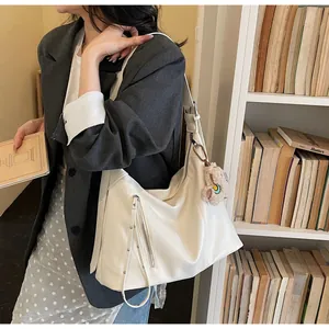 Détail d'un sac cabas minimaliste crème avec fermetures éclair et un charmant ours en peluche