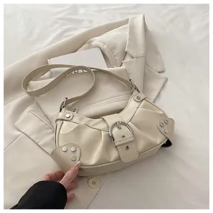Close-up of cream pleated shoulder bag with silver buckle and stud details on a blazer
