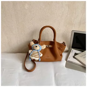 Detail of brown litchi pattern bucket bag with a cute bear charm and shoulder strap