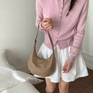 Brown hobo crescent bag with silver zipper on model in a minimalist home setting