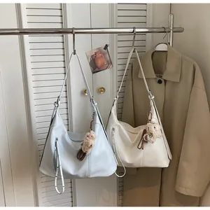 Gros plan de sacs hobo minimalistes en bleu clair et crème avec pendentifs agneau