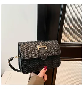 Close-up of black woven leather square bag featuring a gold rectangular metal buckle clasp