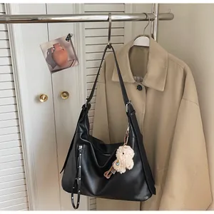 Détail du sac hobo noir en cuir mat avec un joli porte-clés en peluche en forme d'alpaga
