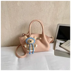 Close-up of pink bucket bag with lychee texture and cute teddy bear charm detail