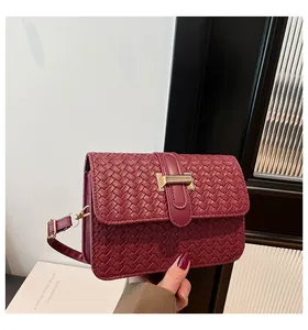 Detail of burgundy woven leather square bag with elegant gold metal buckle closure