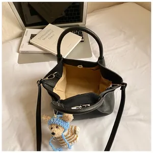 Detail view of black pebble leather bucket bag with teddy bear charm and spacious interior