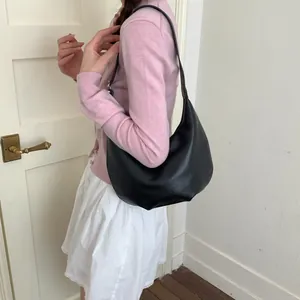 Side view of a woman wearing a black leather crescent hobo bag for a stylish commute