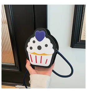 Close-up of cupcake-shaped crossbody bag with blue woven strap and heart detail