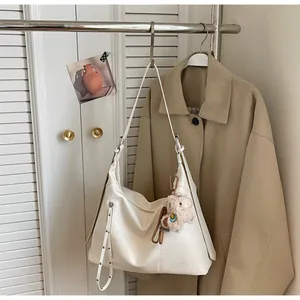 Détail d'un cabas en cuir crème avec pendentif mouton en peluche et texture grainée