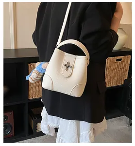 Detail view of cream bucket bag with litchi grain leather and silver twist lock on model