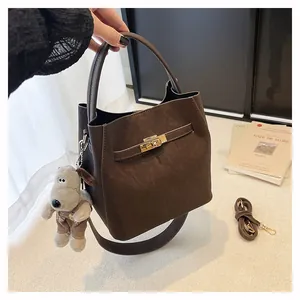 Detail der dunkelbraunen Beuteltasche mit goldenem Drehverschluss und Hund-Anhänger
