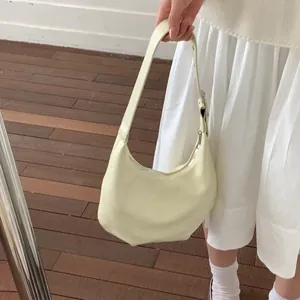 Detail showing creamy yellow crescent underarm bag with adjustable strap and silver buckle