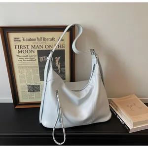 Détail d'un sac cabas en cuir bleu clair avec fermeture éclair argentée sur support bois