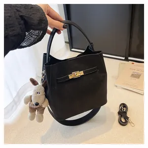 Details einer schwarzen matten Beuteltasche mit goldenem Drehverschluss und Hundeanhänger