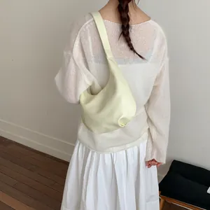 Minimalist cream crescent shoulder bag shown from behind on a female model