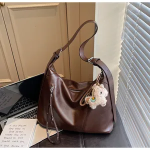 Détail du sac Hobo marron foncé avec fermeture éclair à pompon et pendentif alpaga en peluche
