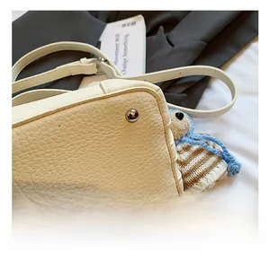 Detail of beige lychee grain bucket bag showing silver hardware feet and strap