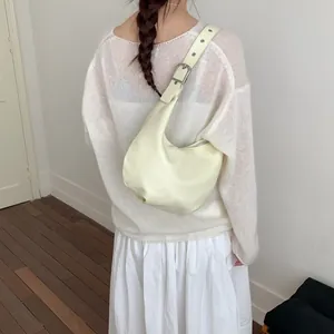 Close-up of cream crescent hobo bag featuring adjustable wide strap with silver grommets