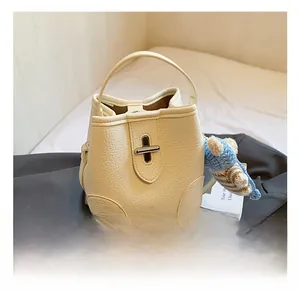 Detail of creamy white bucket bag with pebble leather texture and metal swivel lock
