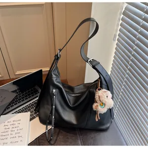 Détail du sac hobo noir avec fermeture éclair à franges et petit pendentif ours peluche
