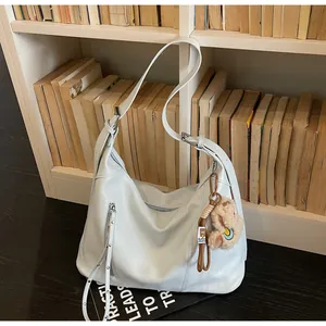 Détail du sac hobo en cuir bleu clair avec bandoulière réglable et pendentif ours