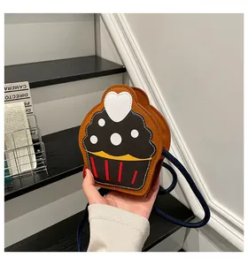 Close-up of cupcake shaped crossbody bag with woven rope strap and heart detail