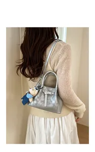 Silver bucket bag with strap and plush bear charm shown in a lifestyle model shot