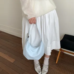 Light blue leather crescent hobo bag styled with a white outfit and adjustable strap