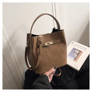 Detail einer braunen matten Leder-Beuteltasche mit goldenem Drehverschluss und Henkel