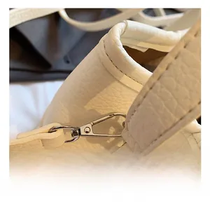 Detailed close-up of premium silver metal hooks on a white litchi pattern leather bag
