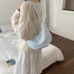 Close-up of baby blue leather hobo crescent bag worn over a woman's shoulder