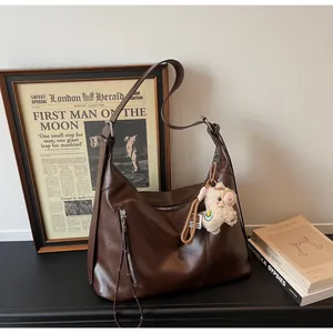 Détail du sac hobo en cuir marron foncé avec fermeture éclair et charm mouton