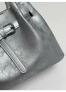 Close-up of metallic silver bucket bag featuring leather straps and silver buckle detail