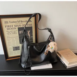 Vue détaillée du sac hobo noir minimaliste avec poche zippée et charmant pendentif en peluche